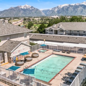 Shimmering resort-style pool a swimming pool with a deck and chairs and a building in the background